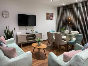 sala de estar con mesa, sillas y TV en Turista en casa Apartamento con 100 m2, en Lima