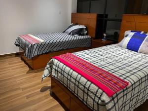 two beds in a room with wooden floors at Turista en casa Apartamento con 100 m2 in Lima