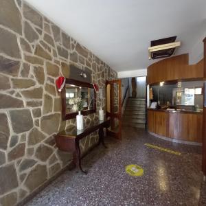 a lobby with a stone wall and a table with a mirror at Hotel Meson in Pinamar