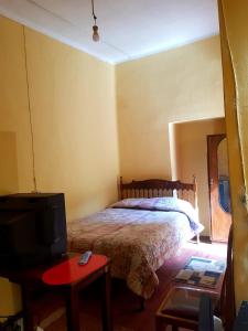 1 dormitorio con 1 cama y TV. en Casa de Huespedes Concordia en Cochabamba