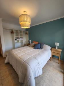 a large bed in a bedroom with a blue wall at Andes Departamentos in El Bolsón