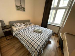 a small bedroom with a bed with a plaid blanket at Lullaby Private Rooms in Poznań
