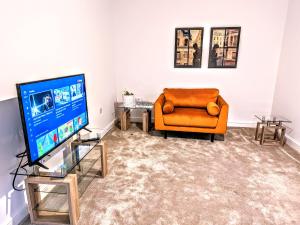 uma sala de estar com uma cadeira laranja e uma televisão em Lovely 3 Bed Home for Colleagues em Darlington