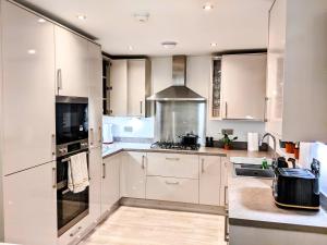 La cuisine est équipée de placards blancs et d'un four avec plaques de cuisson. dans l'établissement Lovely 3 Bed Home for Colleagues, à Darlington