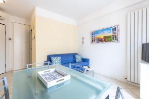 a living room with a glass table and a blue couch at Apartment Holiday Senigallia in Senigallia