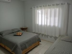 a bedroom with a bed and a window with curtains at Casa da Thalita in Pirenópolis