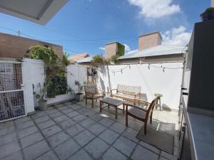 a patio with two benches and a table and chairs at Casa Tila in Puerto Madryn
