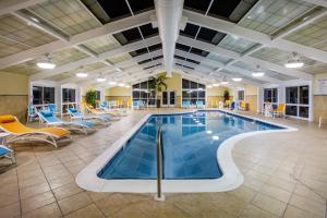 einen Pool in einer Hotellobby mit Stühlen und Tischen in der Unterkunft Holiday Inn - Gulfport-Airport, an IHG Hotel in Gulfport