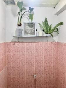 ein Badezimmer mit rosa gefliesten Wänden und einem Regal mit Pflanzen in der Unterkunft LORENT HOSTEL in Kampungdurian