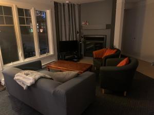 Una sala de estar con dos sofás y una mesa. en Condo Lac Archambault 316, en Saint-Donat