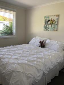 a large white bed with a teddy bear sitting on it at Cape View B and B in Table Cape