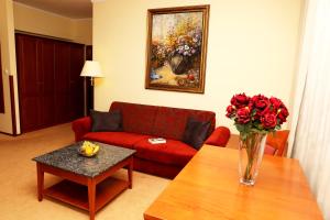 een woonkamer met een rode bank en een vaas met bloemen op een tafel bij Hotel Matyšák in Bratislava