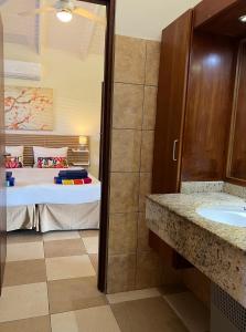 1 dormitorio con 1 cama y baño con lavamanos en Vrijstaande BB BEACH Villa Azure, en Blue Bay