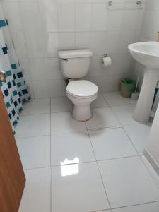 a white bathroom with a toilet and a sink at Casa Quelita in Punta de Choros
