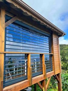 una ventana en una casa con vistas al océano en Papaye Lodge sur les flancs des Monts Caraïbes, en Vieux-Fort