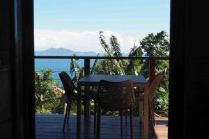 una mesa y sillas en un balcón con vistas al océano en Papaye Lodge sur les flancs des Monts Caraïbes en Vieux-Fort