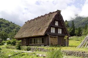 uma casa antiga com um telhado de palha num campo em TOYOTA Shirakawa-Go Eco-Institute em Shirakawa