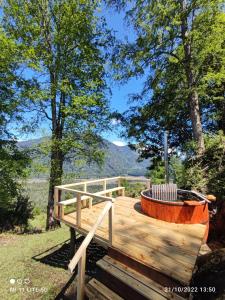 a wooden deck with a fire pit and trees at cabaña vista nilahue in Ranco