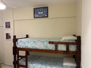 2 letti a castello in una camera con un orologio a muro di APARTAMENTO NA PRAIA GRANDE A 200 MÉTROS DA PRAIA, CONFORTÁVEL ESPAÇOSO WIFI 350 Mega TV Claro, ÓTIMA LOCALIZAÇÃO a Praia Grande Altre 99 foto