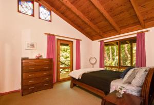 a bedroom with a bed and a dresser and windows at Falls Lodge - a Blue Mountains experience in Wentworth Falls