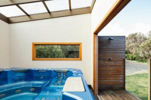 La salle de bains est pourvue d'une baignoire bleue située à côté d'une porte. dans l'établissement Birdsong Hideaway, à Saint Andrews Beach