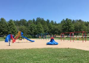 un parque con parque infantil con toboganes y equipo de juegos en Condo Lac Archambault 305 en Saint-Donat-de-Montcalm