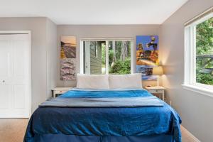 een slaapkamer met een blauw bed en 2 ramen bij Reef Point Retreat in La Conner