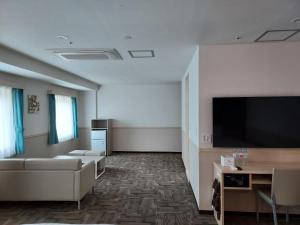 昌原市にあるToyoko Inn Changwonのソファと薄型テレビのあるリビングルーム