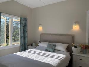 a bedroom with a bed with white sheets and a window at Bridgehouse Lodge in Warkworth