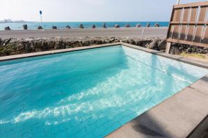 uma piscina com uma cadeira e o oceano em Aqua Beautique Poolvilla em Jeju