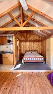 1 dormitorio con 1 cama en una habitación con suelo de madera en Cabañas Bosque las Trancas en Las Trancas