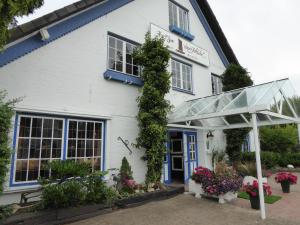 un edificio blanco con una puerta azul y flores en Hotel zum alten Torfkahn en Osterholz-Scharmbeck