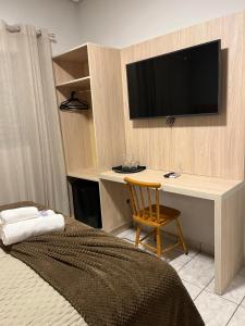 a bedroom with a desk and a television on a wall at POUSADA ACONCHEGO MT in Chapada dos Guimarães