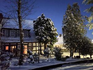 una casa con árboles nevados delante de ella en Hotel zum alten Torfkahn, en Osterholz-Scharmbeck