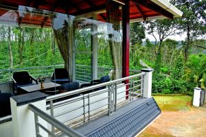 a porch of a house with a table and chairs at Estate Flora Homestay - Balcony, Home Food, Coffee Estate in Sakleshpur