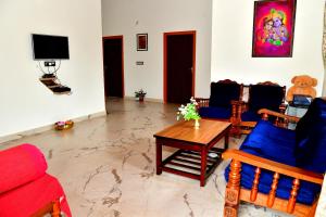 a living room with chairs and a table and a tv at Estate Flora Homestay - Balcony, Home Food, Coffee Estate in Sakleshpur