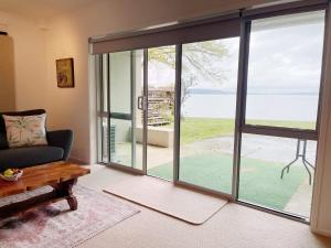 a living room with sliding glass doors with a view of the ocean at Lakeside & Tennis Court Paradise in Rotorua