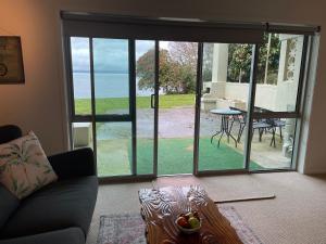 salon z przesuwnymi szklanymi drzwiami prowadzącymi na patio w obiekcie Lakeside & Tennis Court Paradise w mieście Rotorua