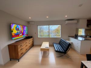 a living room with a tv and a couch and a table at Sakura Apartments in Kutchan