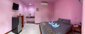 uma sala de estar com paredes cor-de-rosa e um sofá em PK Family House em Ko Mook