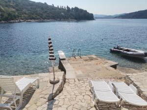a dock with chairs and a boat in the water at Villa Rosa in Vela Luka