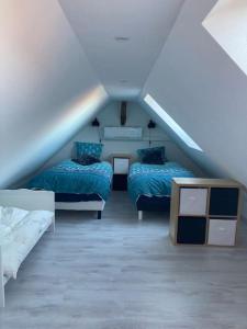 a attic room with two beds and a table at Juste un rayon de soleil Proche Europa-park in Saasenheim