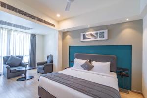 um quarto de hotel com uma cama grande e uma cadeira em REPUBLIC INN em Tirupati