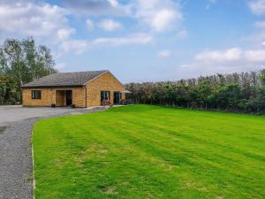 una casa con un gran campo de hierba delante de ella en Grange Garth Cottage en Acaster Malbis