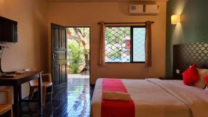a bedroom with a bed and a desk and a window at Garden Villa in Vagator
