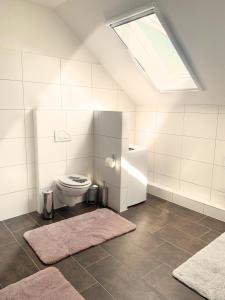 a white bathroom with a toilet and a skylight at Kastanienhof in Südbrookmerland