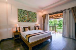 a bedroom with a bed and a large window at Uma Dawa Resort and Spa in Ubud