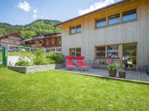 un patio con 2 sillas rojas y un edificio en Felder Apartments, en Schoppernau