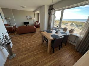 een woonkamer met een tafel en stoelen en een groot raam bij Appartementen Zeezicht - 3 in Katwijk aan Zee