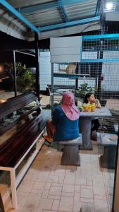 a woman sitting at a picnic table with a bird at Aleesa Roomstay in Pasir Puteh